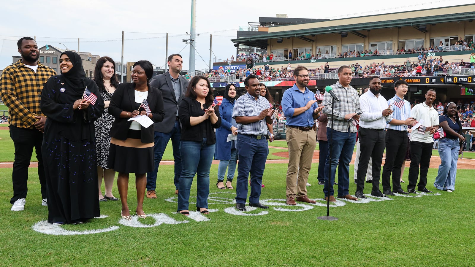 Twenty immigrants became U.S. citizens during a naturalization ceremony on Tuesday, Aug. 5, between the third and fourth innings of a Dayton Dragons game at Day Air Ballpark. BRYANT BILLING / STAFF