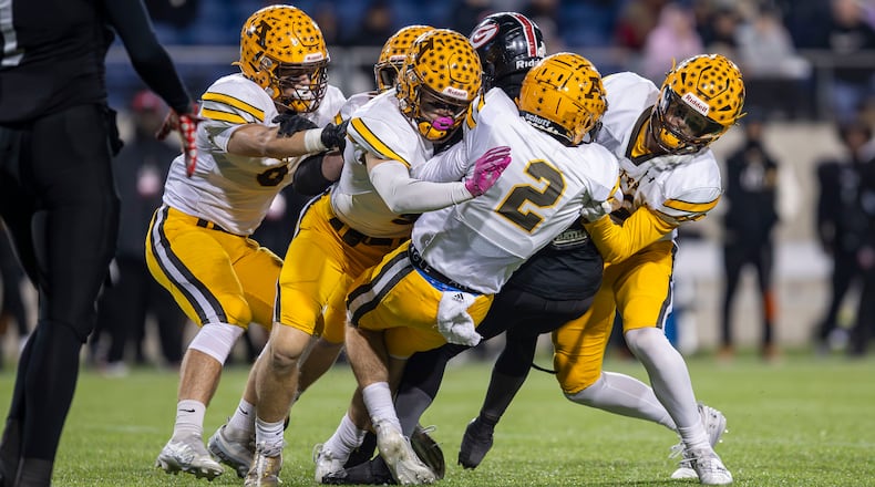 A group of Alter players make a tackle during the Division IV state championship game against Cleveland Glenville on Saturday night at Tom Benson Hall of Fame Stadium in Canton. CONTRIBUTED PHOTO BY MICHAEL COOPER