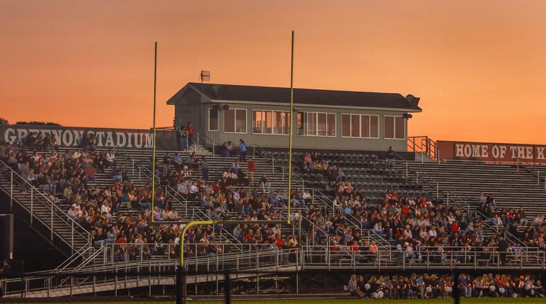 A crowd holds candles during a candlelight vigil on Wednesday, October 8, 2025, at Greenon Stadium, to honor Greenon students Nevin Vince and Natalie Daly who were killed in a Huber Heights crash. JOSEPH COOKE / STAFF