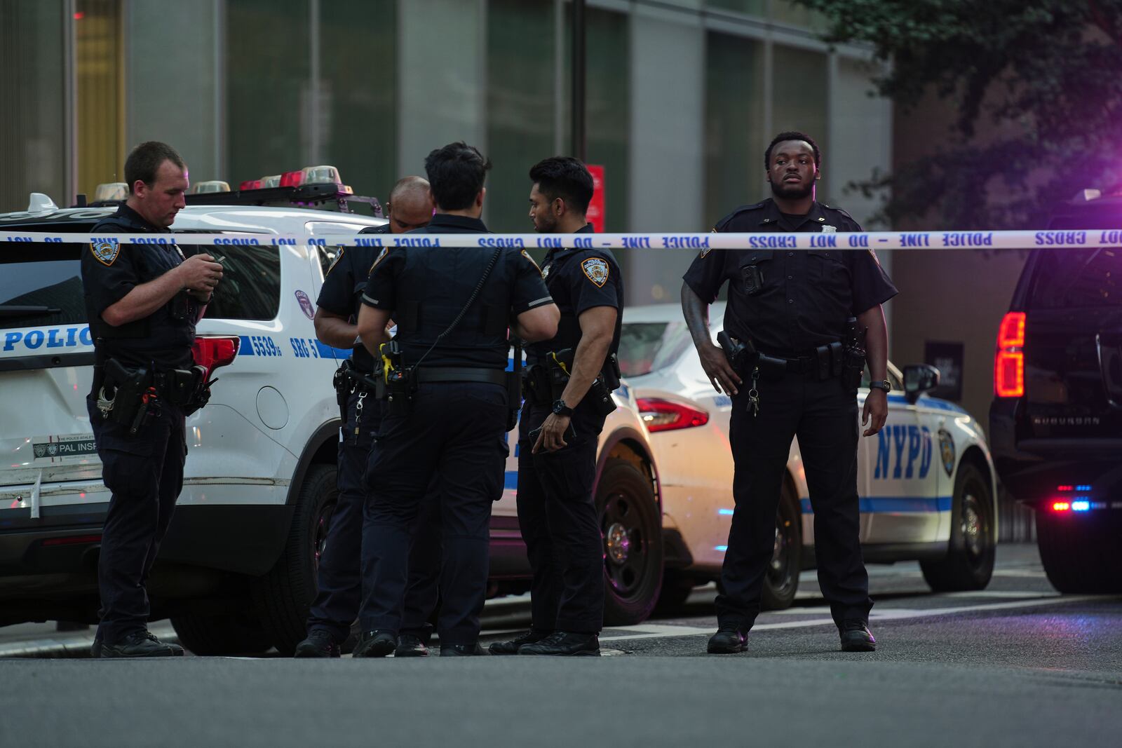 A New York Police officers gather at the scene on 52nd Street outside a Manhattan office building where two people were shot, including a New York police officer, Monday, July 28, 2025, in New York. (AP Photo/Angelina Katsanis)