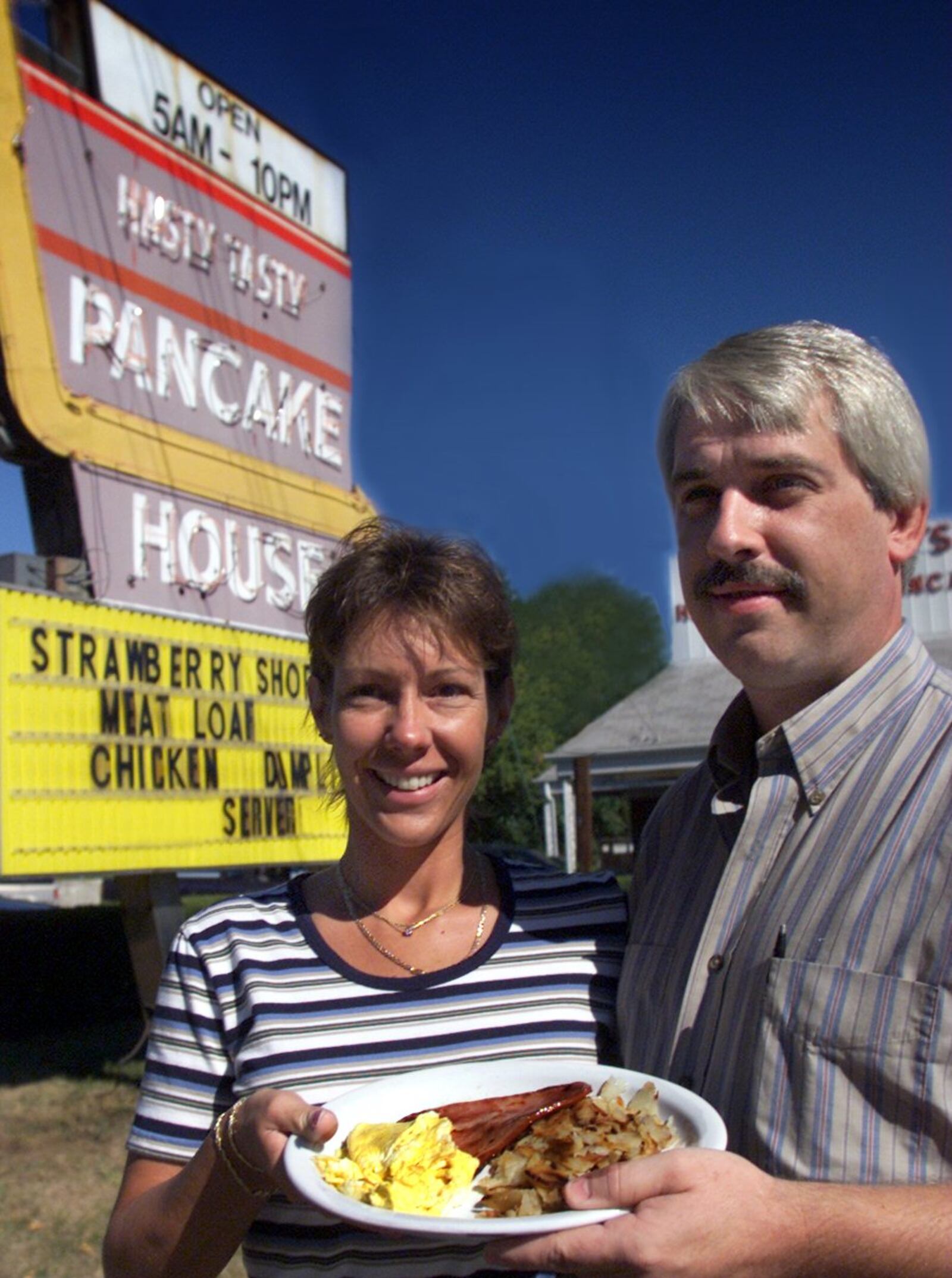Mike Hackman (R), the owner of the Hasty-Tasty Pancake House, and his wife Michelle stand outside the east side restaurant with one of their big breakfasts.