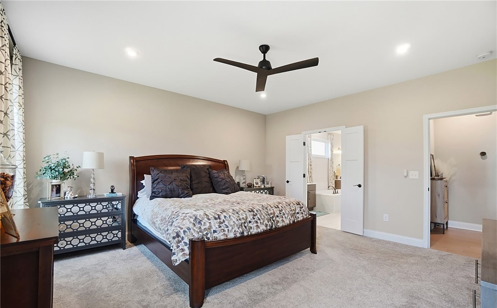 The first floor primary bedroom suite has neutral carpeting, a ceiling fan and recessed lighting. The ensuite bathroom features tile flooring, a soaking tub and walk in shower and an oversized walk in closet. CONTRIBUTED