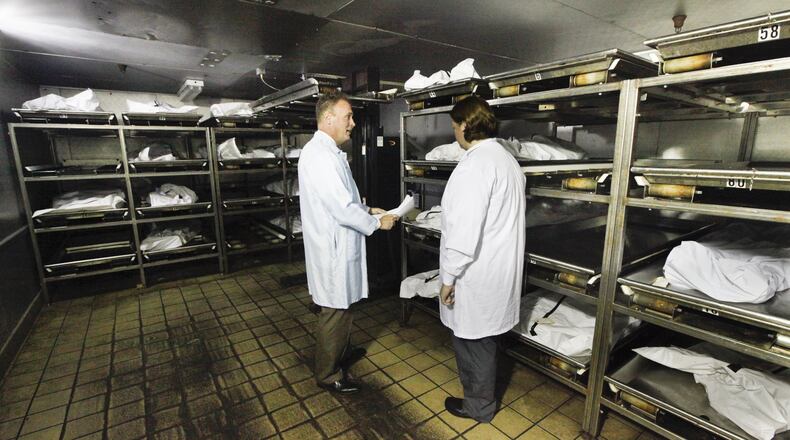 Montgomery County Coroner Dr. Kent Harshbarger, left, and pathology technician Michelle Welch are seen in the cooler at the morgue where an increase in drug overdose deaths has been reported. CHRIS STEWART / STAFF