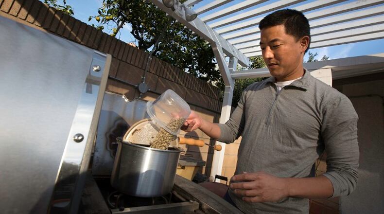 Los Angeles Times reporter Jason Song pours green coffee beans in a popcorn popper to roast on his patio BBQ grill burner at his home in South Pasadena, Calif., on Nov. 8, 2015. (Brian van der Brug/Los Angeles Times/TNS)