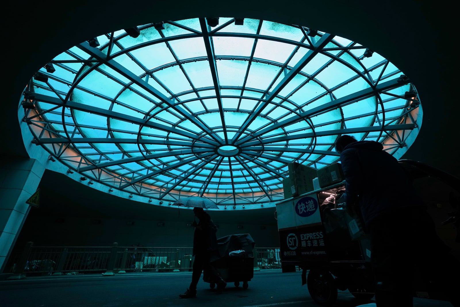 Delivery couriers sort out parcels for their customers underneath a tunnel during a rainy day in Beijing, Friday, May 9, 2025. (AP Photo/Andy Wong)
