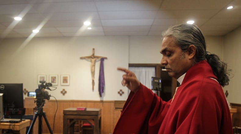 Father Satish Joseph directs his crew before livestreaming a service on Good Friday afternoon. JIM NOELKER/STAFF