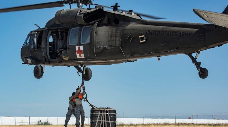 Second Lt. Adam Brewer from the Air Force Life Cycle Management Center’s Business and Enterprise Systems Directorate, is braced by Staff Sgt. Matthew Garside from the 26th Aerial Port Squadron, as he attaches an A-22 cargo bag with 2,000 pounds of ‘relief supplies’ to the cargo hook of a UH-60 Black Hawk helicopter flown by Soldiers from the Texas Army National Guard Company C, 2-149 Aviation during Operation Alamo Evacuation Nov. 18 at Martindale Army Airfield, Texas. About 36,000 pounds of cargo and 27 passengers were transported as part of the sling load and medical evacuation exercise.