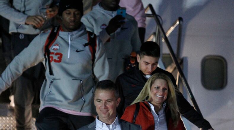 Ohio State head coach Urban Meyer, center, exits a plane after arriving with his team at Phoenix Sky Harbor Airport on Monday Dec. 26, 2016, in Phoenix. Ohio State will play Clemson in the Fiesta Bowl as part of the college football playoff semifinal on Dec. 31, 2016. (AP Photo/Ralph Freso)