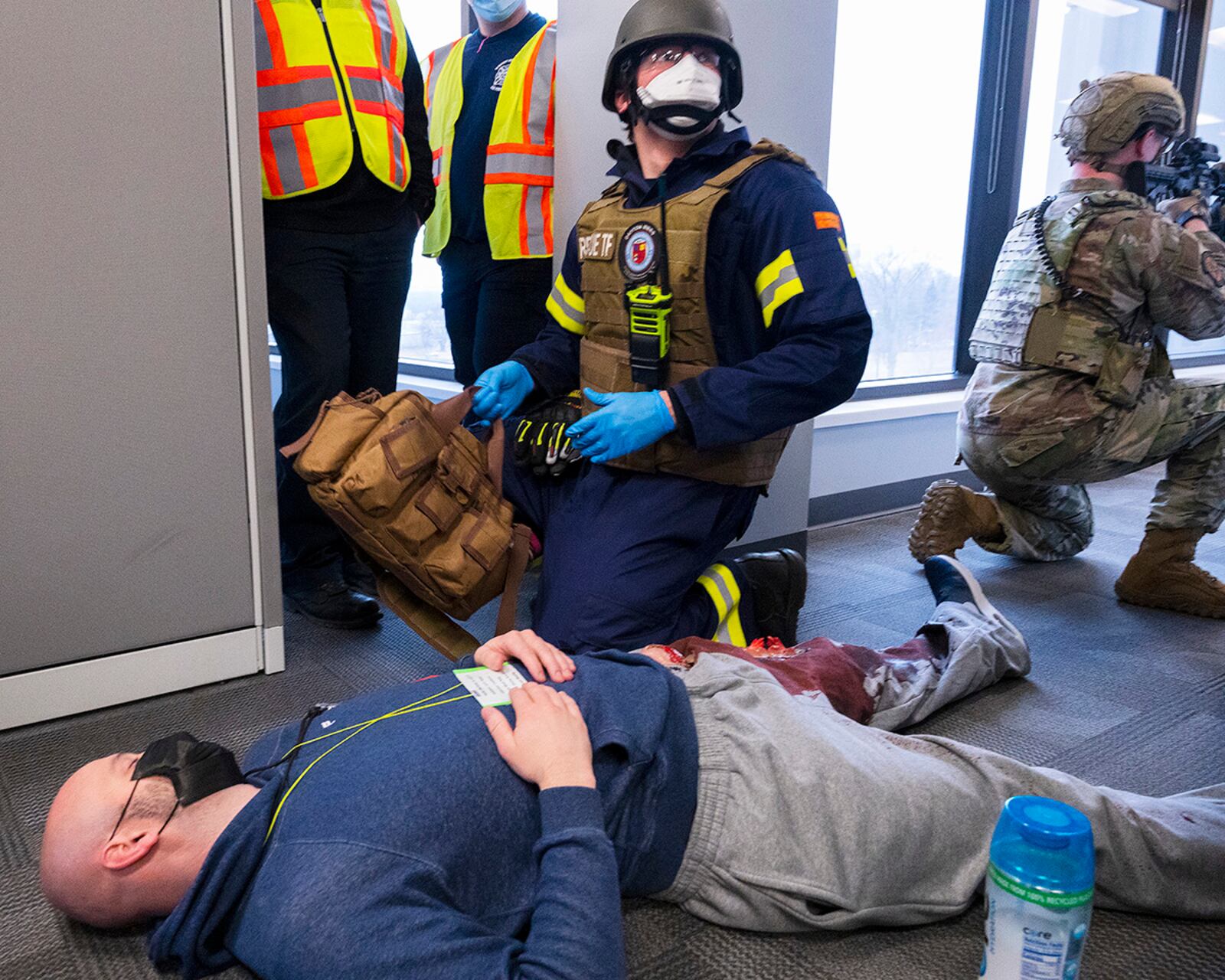 A paramedic with Rescue Task Force checks on a shooting “victim” as an 88th Security Forces Squadron Defender provides cover and exercise observers look on during the active-shooter exercise Feb. 23 at Wright-Patterson Air Force Base. U.S. AIR FORCE PHOTO/R.J. ORIEZ
