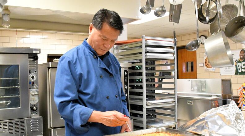 Art Chin, long-time chef and restaurant owner in Dayton and Tipp City, checks food being prepared as part of his new job in the kitchen at Broadway Elementary School in Tipp City. CONTRIBUTED