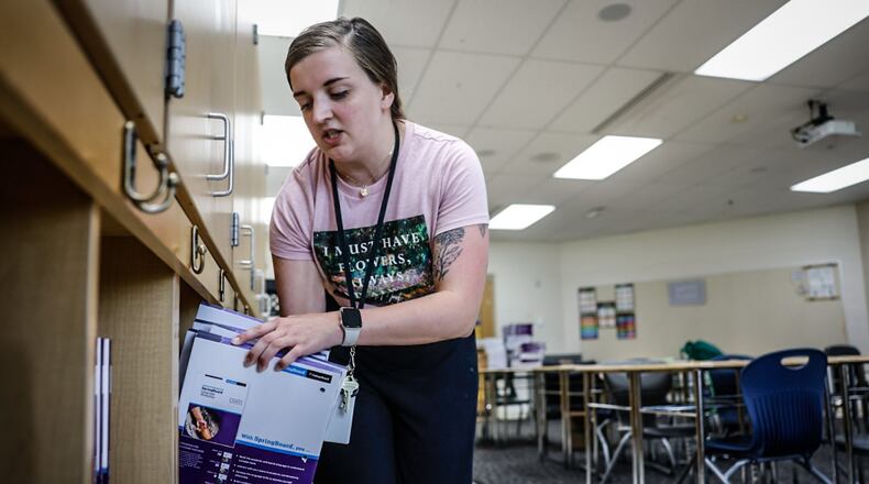 Amy Conrad, a first-year teacher for Dayton Public Schools, stacks books onto shelves Thursday, Aug. 10 in her classroom at E.J. Brown Middle School in preparation for the first day of school Monday. JIM NOELKER/STAFF