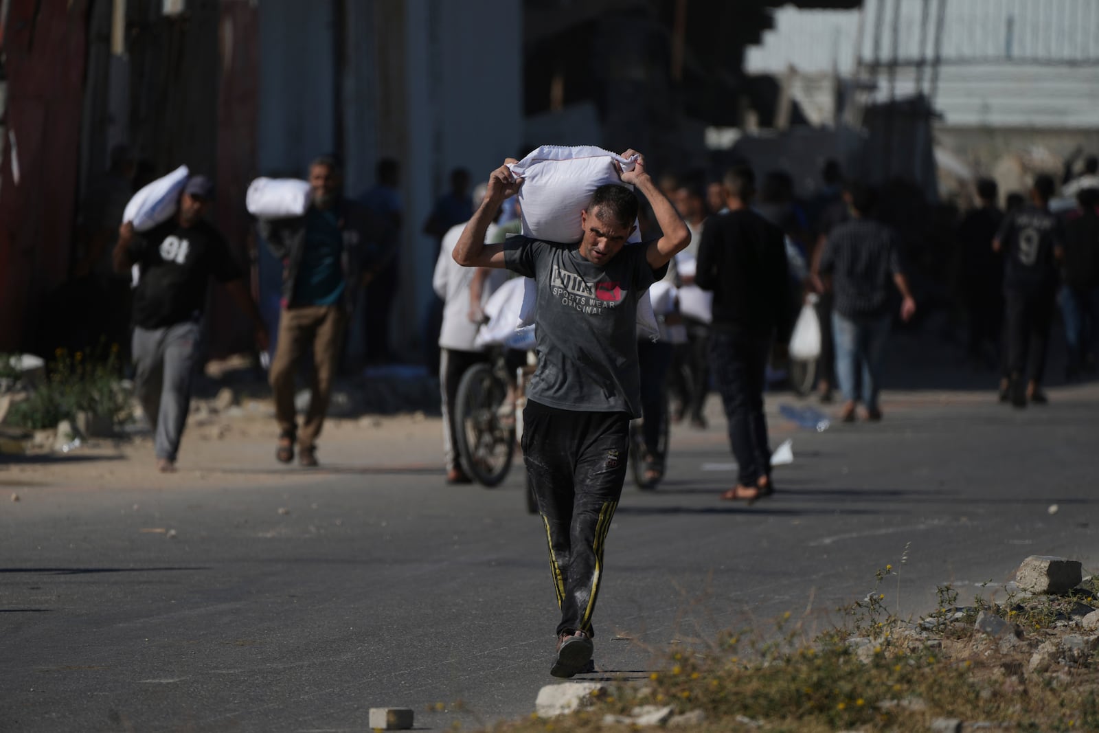 Palestinians carry bags of flour after storming a U.N. World Food Program warehouse in Zawaida, Central Gaza Strip, on Wednesday, May 28, 2025. (AP Photo/Abdel Kareem Hana)