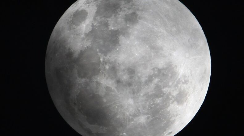 In this Monday Feb. 9, 2009 photo, a faint shadow from the Earth is cast over part of the Moon during a penumbral lunar eclipse, seen from Manila, Philippines. Early Saturday, Feb. 11, 2017, a partial eclipse and Comet 45P will share the sky. BULLIT MARQUEZ/ASSOCIATED PRESS
