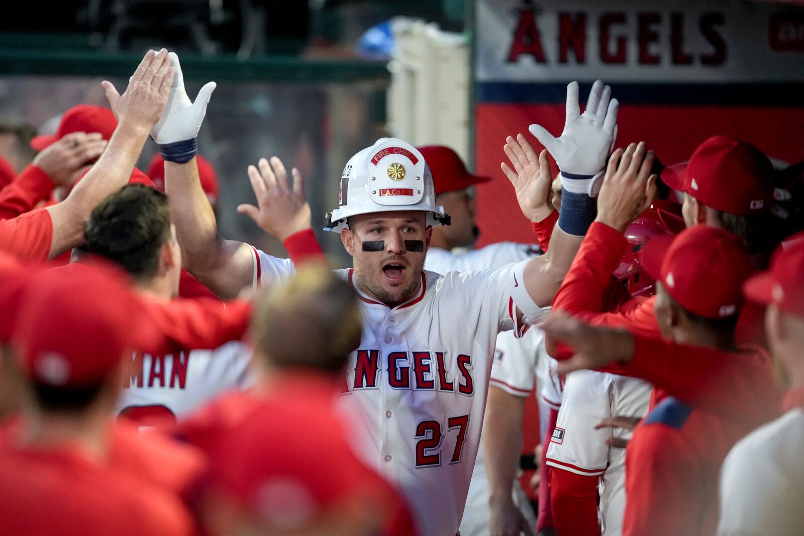 Los Angeles Angels' Mike Trout (27) celebrates with teammates in the dugout after hitting a home run during the first inning of a baseball game against the Cleveland Guardians in Anaheim, Calif., Friday, April 4, 2025. (AP Photo/Eric Thayer)