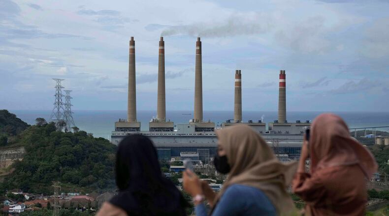 FILE - Women sit on a hill overlooking the Suralaya coal power plant in Cilegon, Indonesia, Jan. 8, 2023. (AP Photo/Dita Alangkara, File)