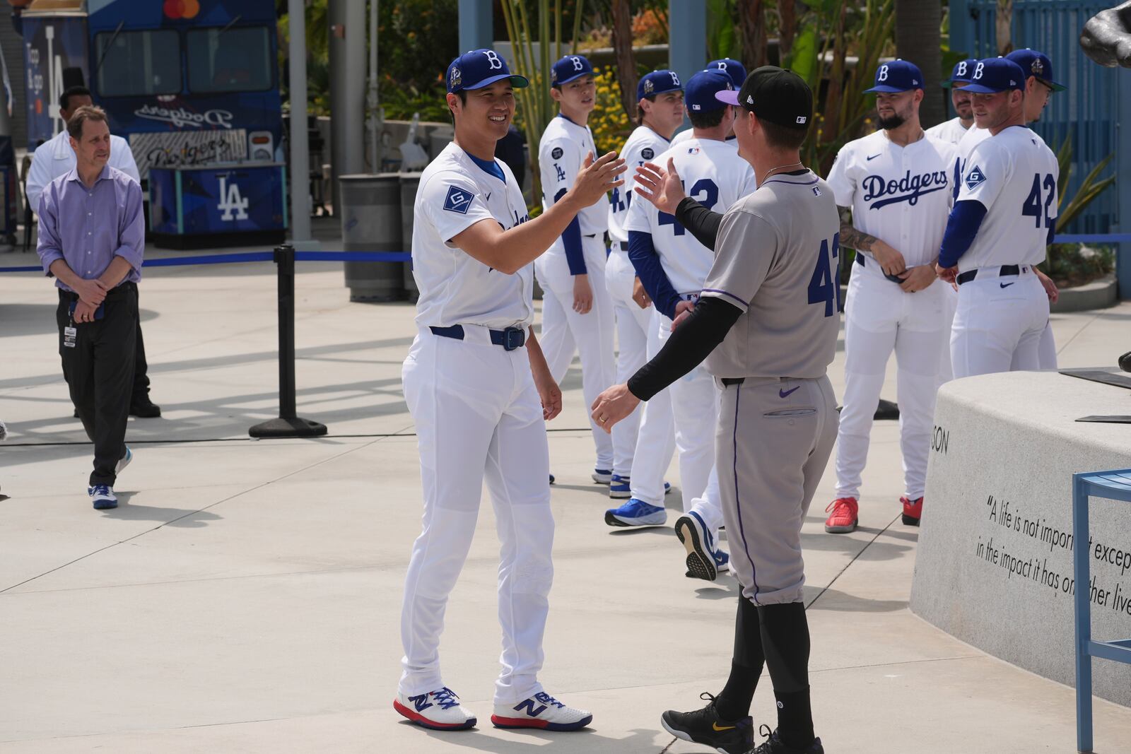 Los Angeles Dodgers' Shohei Ohtani, left, shakes hands with a member of the Colorado Rockies at Dodger Stadium during an event to commemorate Jackie Robinson Day before a baseball game Tuesday, April 15, 2025, in Los Angeles. (AP Photo/Damian Dovarganes)