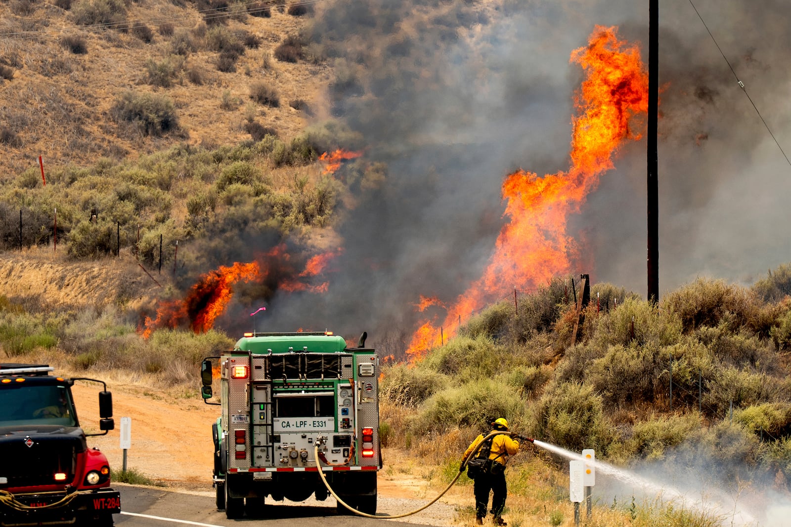 A firefighter battles the Madre Fire as it makes a run along Highway 166, Thursday, July 3, 2025, in San Luis Obispo County, Calif. (AP Photo/Noah Berger)