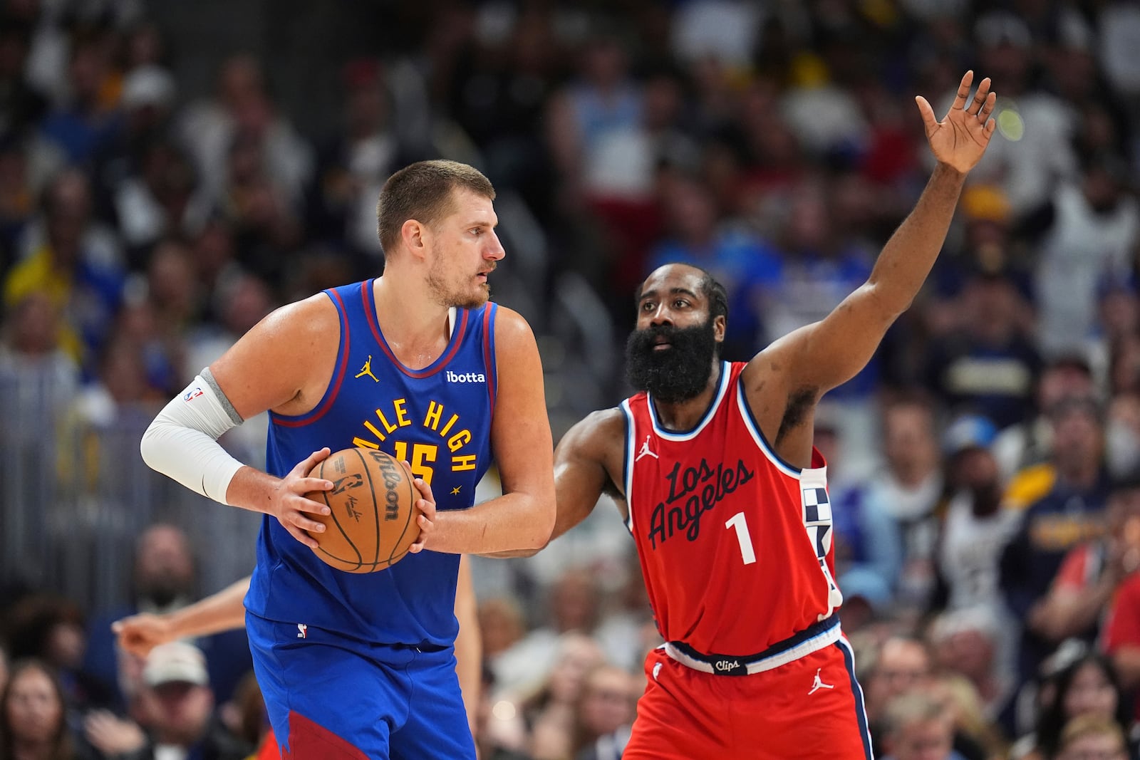 Denver Nuggets center Nikola Jokic, left, looks to pass the ball as Los Angeles Clippers guard James Harden, right, defends in the second half of Game 7 of an NBA basketball first-round playoff series Saturday, May 3, 2025, in Denver. (AP Photo/David Zalubowski)