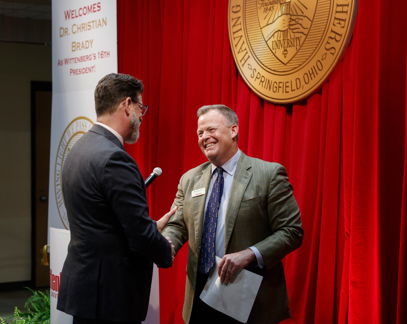 Bill Edwards, center, chair of the board of directors, greets Dr. Christian M. M. Brady during an event where Brady was announced as the 16th president on Friday, May 9, 2025, at Wittenberg University. JOSEPH COOKE/STAFF