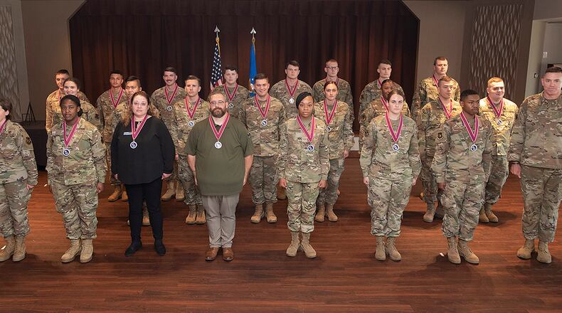 Airman Leadership School Class 21-E poses for a class photo with Col. Michael Phillips (far left), 88th Air Base Wing vice commander, and Chief Master Sgt. Jason Shaffer (far right), 88 ABW command chief, at the end of its graduation ceremony June 17 inside the Wright-Patterson Club. U.S. AIR FORCE PHOTO/R.J. ORIEZ
