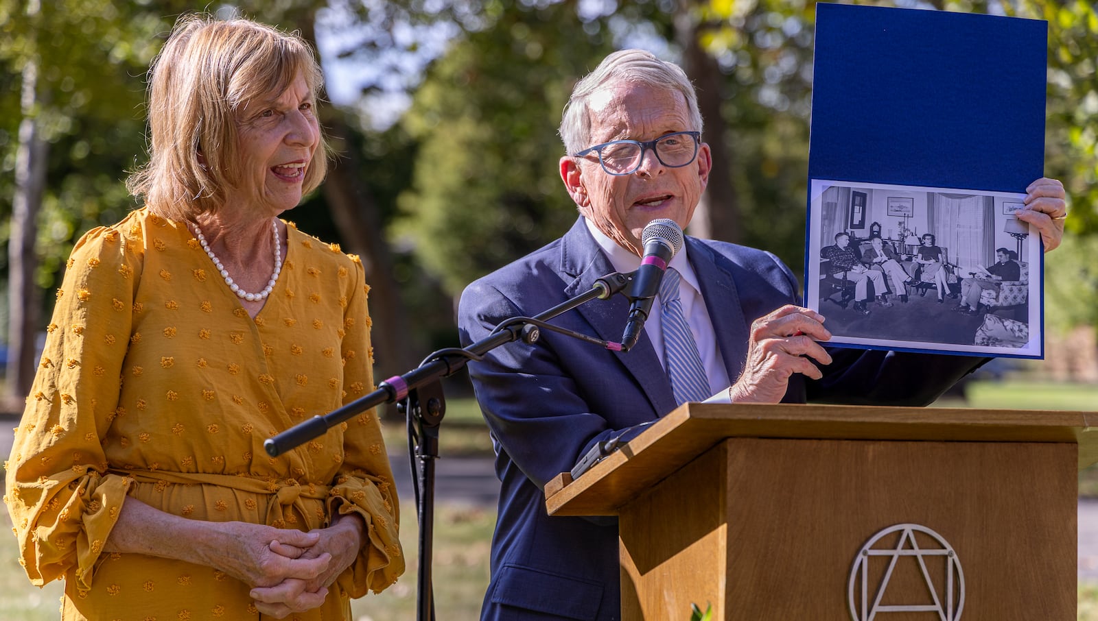 Gov. Mike DeWine holds a photograph that shows Rod Serling sitting on the far right while in the home of his grandparents Albert and Ruth Little during a dedication ceremony for a historical marker for Serling on the campus of Antioch College on Thursday, Oct. 2 in Yellow Springs. DeWine, who is standing next to his wife Fran, said he owns the chair Serling is photographed sitting in. DeWine's grandfather taught at Antioch. BRYANT BILLING / STAFF