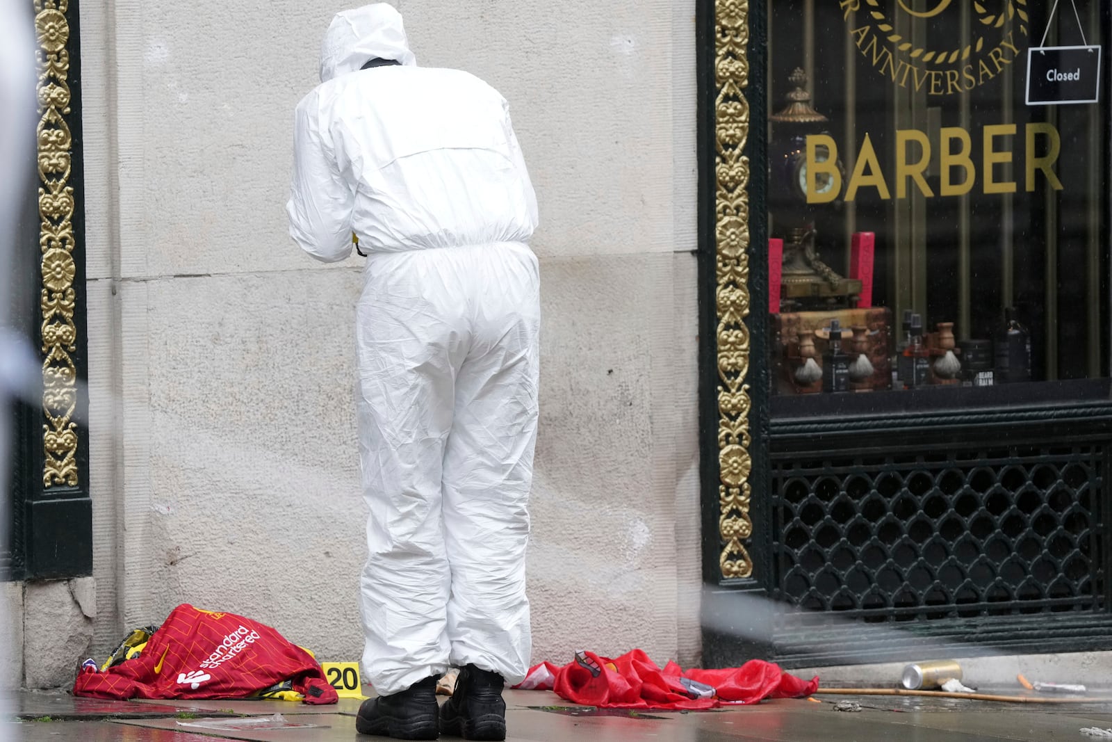 A Forensic officer looks at evidence near the site where a 53-year-old British man plowed a minivan into a crowd of Liverpool soccer fans who were celebrating the city's Premier League championship Monday, injuring more than 45 people in Liverpool, England, Tuesday, May 27, 2025.(AP Photo/Jon Super)