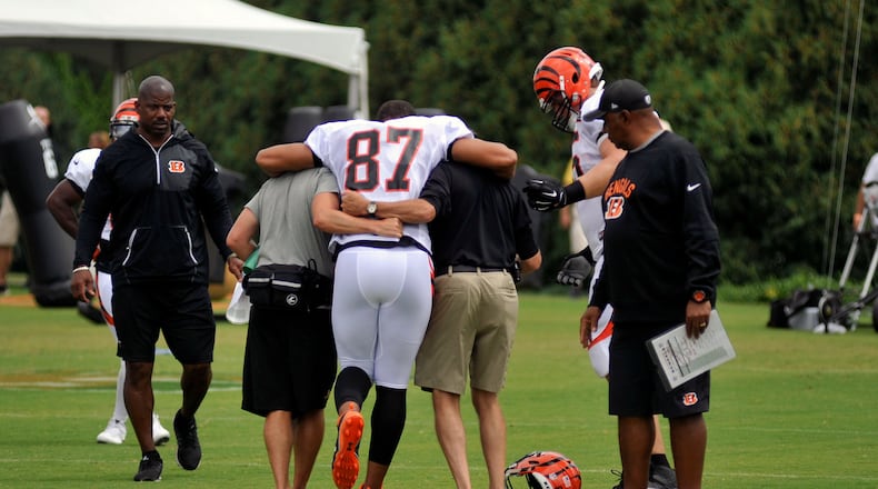 Cincinnati Bengals tight end C.J. Uzomah is helped off the field by trainers Monday as head coach Marvin Lewis looks on. JAY MORRISON/STAFF
