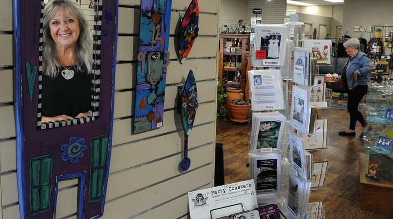 Zig Zag Gallery owner, Kim Megginson is reflected in a mirror at their new larger location at 101 E Alex Bell Road in Centerville. MARSHALL GORBY/STAFF