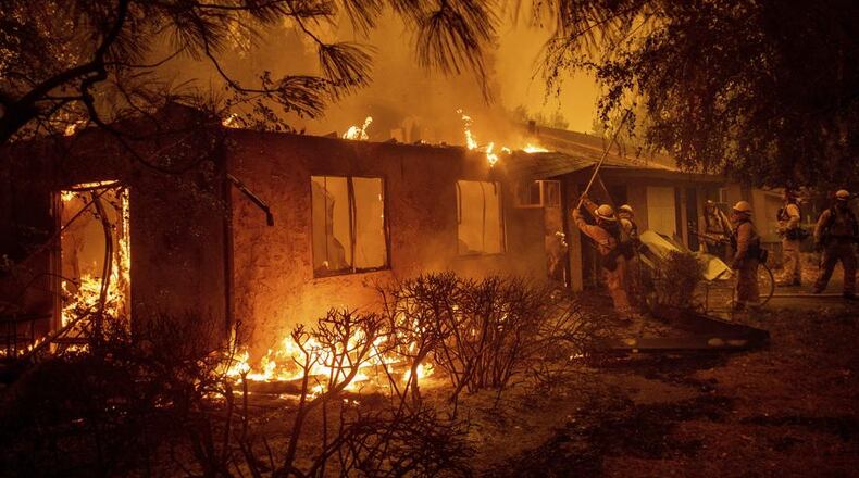 Firefighters work to keep flames from spreading through the Shadowbrook apartment complex as a wildfire burns through Paradise, Calif., on Friday, Nov. 9, 2018. (AP Photo/Noah Berger)