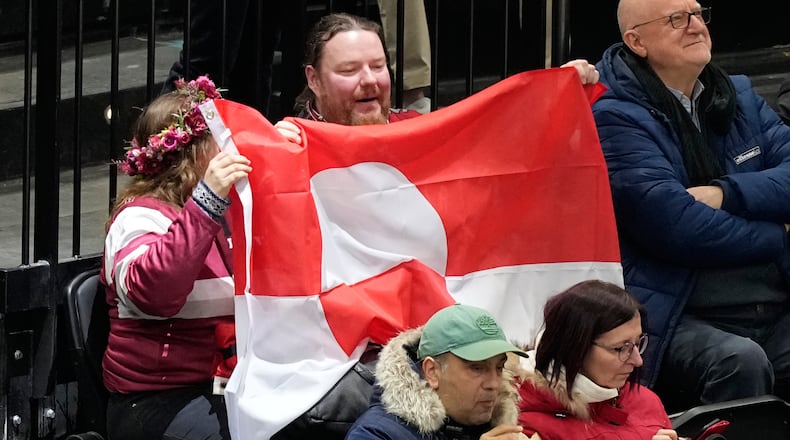 Fans hold Greenland national flag before a preliminary round match of men's ice hockey between United States and Denmark at the 2026 Winter Olympics, in Milan, Italy, Saturday, Feb. 14, 2026. (AP Photo/Hassan Ammar)