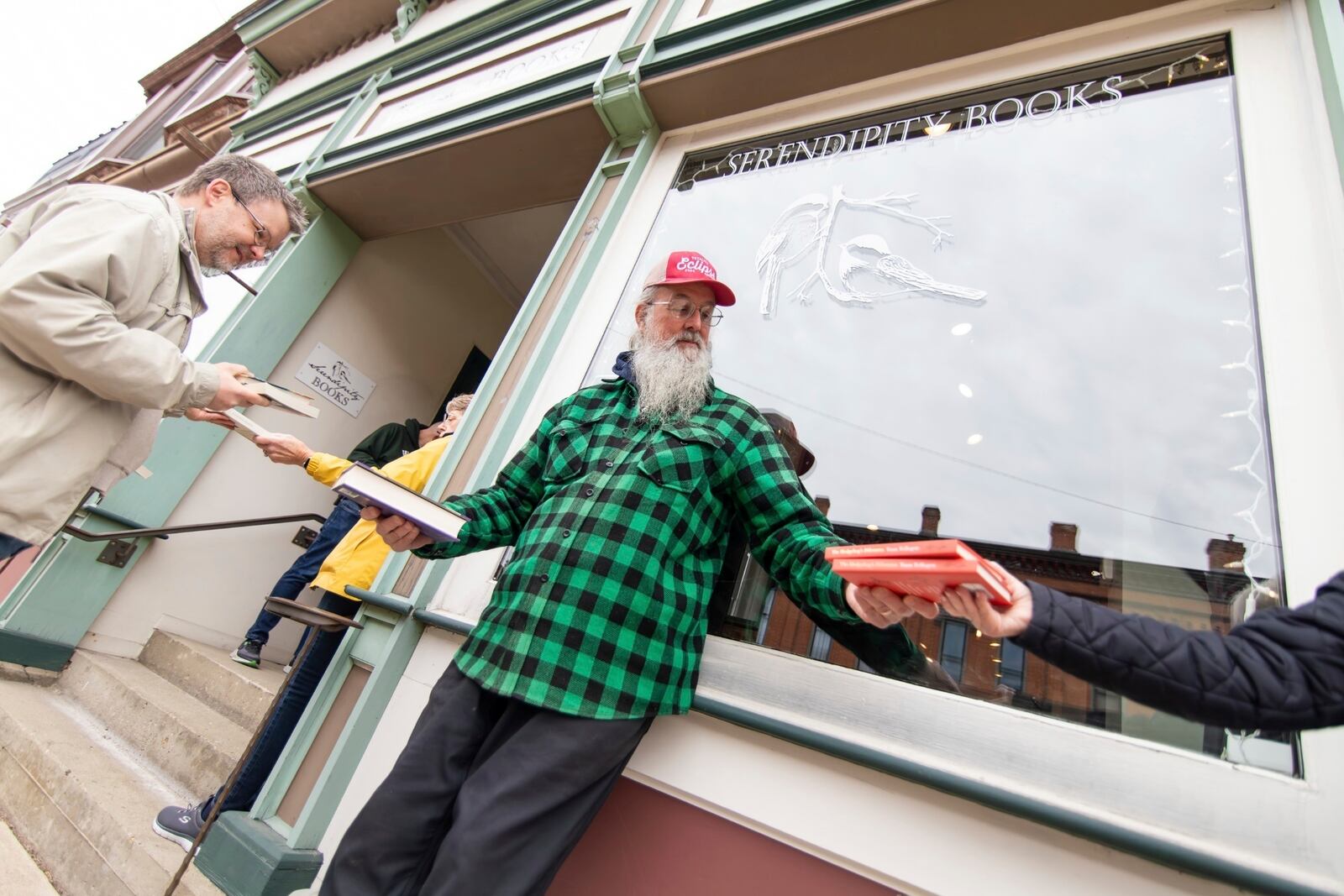 In this photo provided by Burrill Strong, supporters of Serendipity Books pass the store's books hand to hand, helping move the business to a new storefront about a block away from its current location, Sunday, April 13, 2025, in Chelsea, Mich. (Burrill Strong via AP)