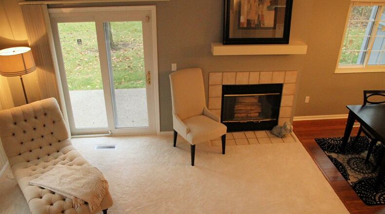 One step down at the end of the entry, the great room sits under a vaulted ceiling with 2 skylights. Tile facing and a white mantel frame the wood-burning fireplace.