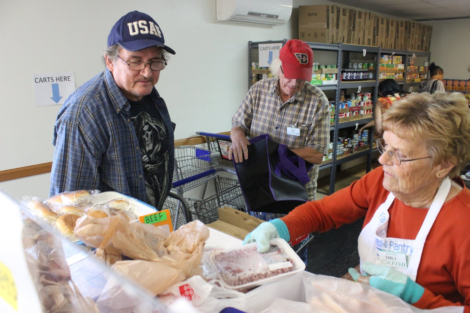 Veteran Dwight Martin Jr., left, selects from the frozen meat selection at the FISH food pantry in Fairborn from volunteer Emily Webb in this 2020 file photo. 