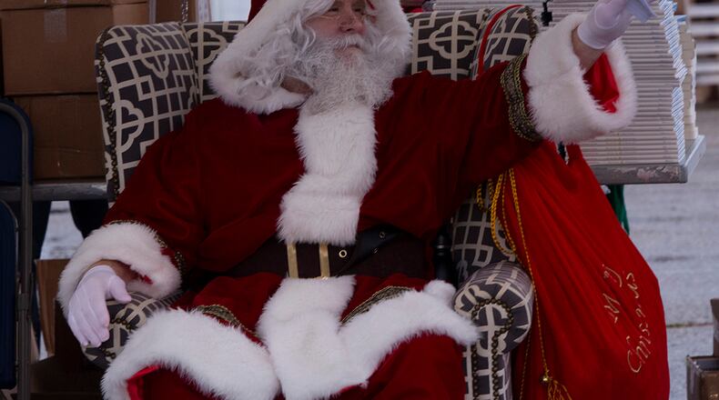 Santa Claus waves to children in a passing vehicle during the 2021 tree lighting drive-thru event Dec. 1 hosted by the 88th Force Support Squadron at Wright-Patterson Air Force Base. Families were able to get goody bags and hot chocolate from Santa’s elves, and then park to watch the base Christmas tree lighting over Facebook Live. U.S. AIR FORCE PHOTO/JAIMA FOGG