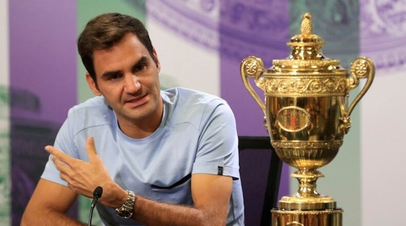 Switzerland's Roger Federer speaks next to the Men's Single's tennis trophy he won on Sunday during a photo call at The All England Lawn Tennis and Croquet Club, Wimbledon, England, Monday July 17, 2017. Federer's eighth Wimbledon title pushed him back up to No.3 in the ATP rankings. (Adam Davy/PA via AP)