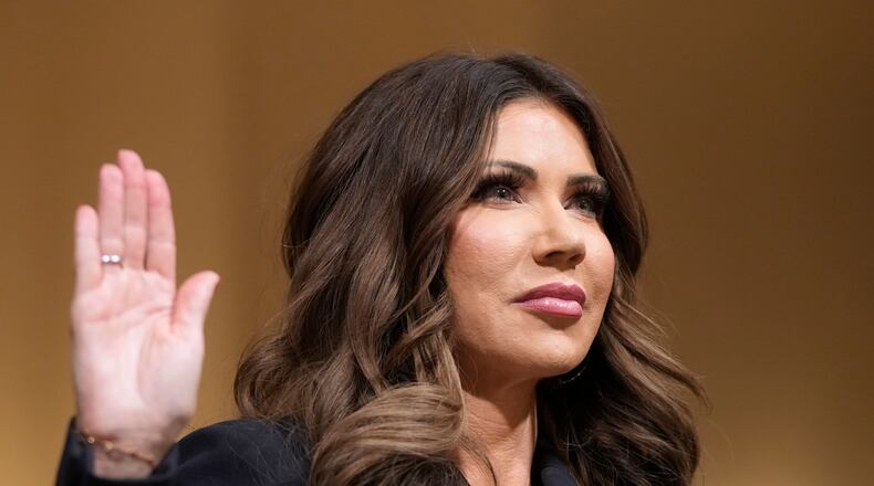 Homeland Security Secretary Kristi Noem raise her arm before the House Committee on Homeland Security on Capitol Hill in Washington, Thursday, Dec. 11, 2025. (AP Photo/Mark Schiefelbein)