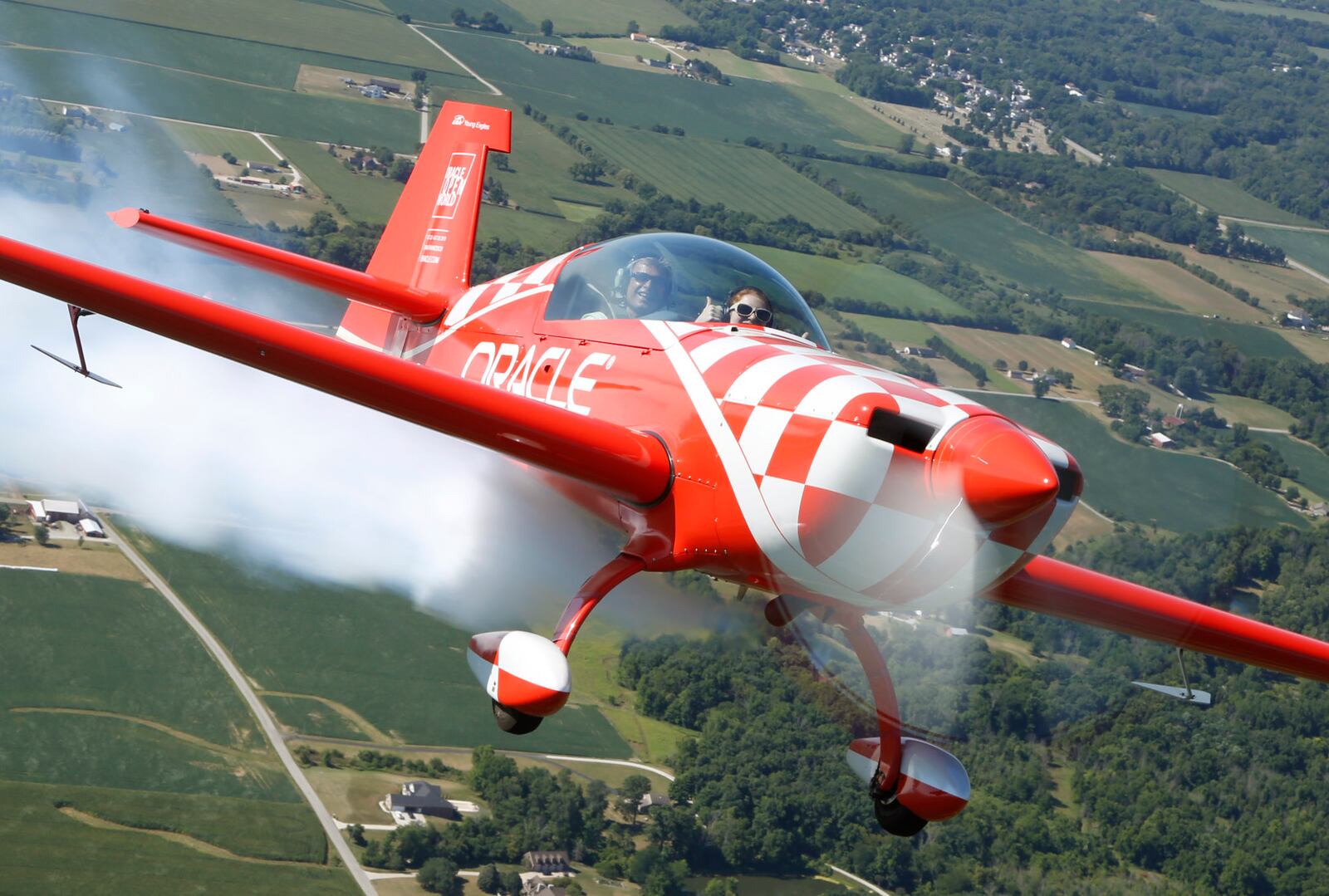 Dayton Air Show Young Eagles essay contest winner Kayla Hughes, 14, waves from the front seat of an aerobatic airplane piloted by legendary pilot Sean D. Tucker in the skies over Miami County.  Hughes originally scheduled flight was cancelled due to poor weather days before the Dayton Air Show in June but Tucker found a way to make it happen on Tuesday in Piqua.   TY GREENLEES / STAFF