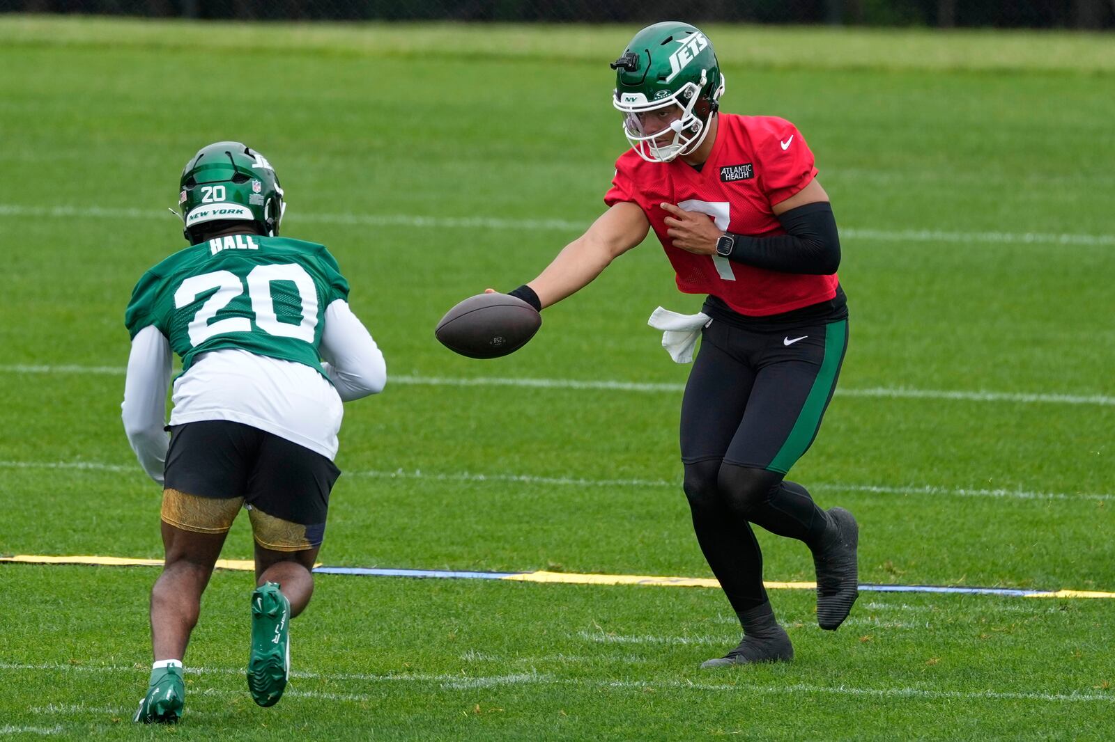New York Jets quarterback Justin Fields (7) hands off to Breece Hall during an NFL football practice in Florham Park, N.J., Thursday, May 29, 2025. (AP Photo/Seth Wenig)