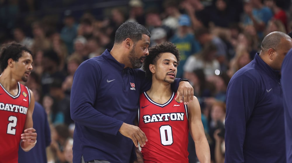 Dayton's Ricardo Greer, left, talks to Javon Bennett during a game against North Carolina Wilmington in the first round of the National Invitation Tournament on Saturday, March 21, 2026, at Trask Coliseum in Wilmington, N.C.. David Jablonski/Staff