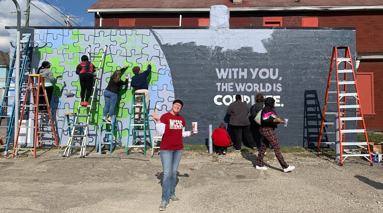 File - Local students and members of the Montgomery County Prevention Coalition in 2022 working on the first of four suicide prevention murals. The first completed mural is located in Old North Dayton at 2232 North Main St. at corner of Main and Fairview. It started as a 36-foot blank purple wall that, with 60 volunteers and an artist with a vision, shared the message, “With you, the world is complete.” COURTESY OF THE MONTGOMERY COUNTY PREVENTION COALITION
