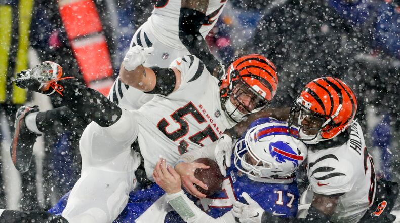 Cincinnati Bengals linebacker Logan Wilson (55) and cornerback Mike Hilton (21) bring down Buffalo Bills quarterback Josh Allen (17) during the fourth quarter of an NFL division round football game, Sunday, Jan. 22, 2023, in Orchard Park, N.Y. (AP Photo/Joshua Bessex)