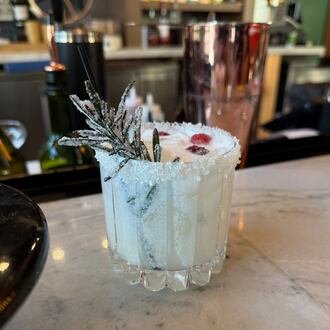 Pictured is the White Christmas cocktail featuring tequila, Cointreau, coconut milk, coconut water and lime juice garnished with sugared rosemary and cranberry. PHOTO COURTESY: BISTECCA