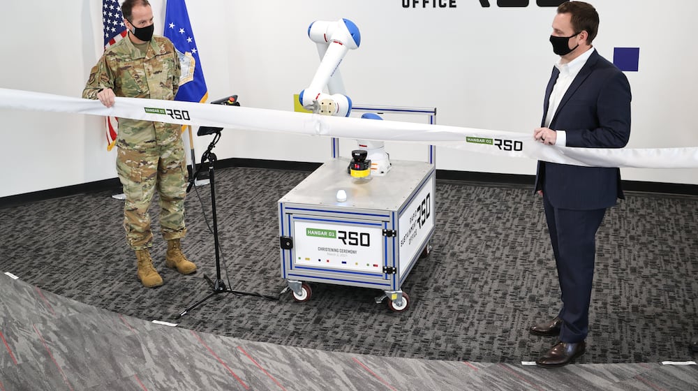 In this 2021 photo, Lt. Gen. Shaun Morris, then-Air Force Life Cycle Management Center commander, and Nathan Parker, Rapid Sustainment Office deputy program executive officer, with the help of a robotic arm, cut the ribbon on Hangar01, an RSO workspace in Dayton. (Air Force photo by Casey Tromp).