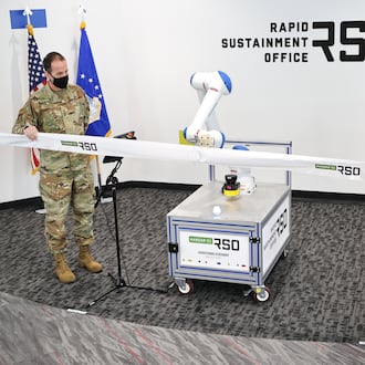 In this 2021 photo, Lt. Gen. Shaun Morris, then-Air Force Life Cycle Management Center commander, and Nathan Parker, Rapid Sustainment Office deputy program executive officer, with the help of a robotic arm, cut the ribbon on Hangar01, an RSO workspace in Dayton. (Air Force photo by Casey Tromp).