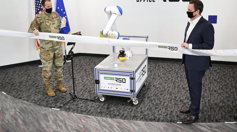 In this 2021 photo, Lt. Gen. Shaun Morris, then-Air Force Life Cycle Management Center commander, and Nathan Parker, Rapid Sustainment Office deputy program executive officer, with the help of a robotic arm, cut the ribbon on Hangar01, an RSO workspace in Dayton. (Air Force photo by Casey Tromp).