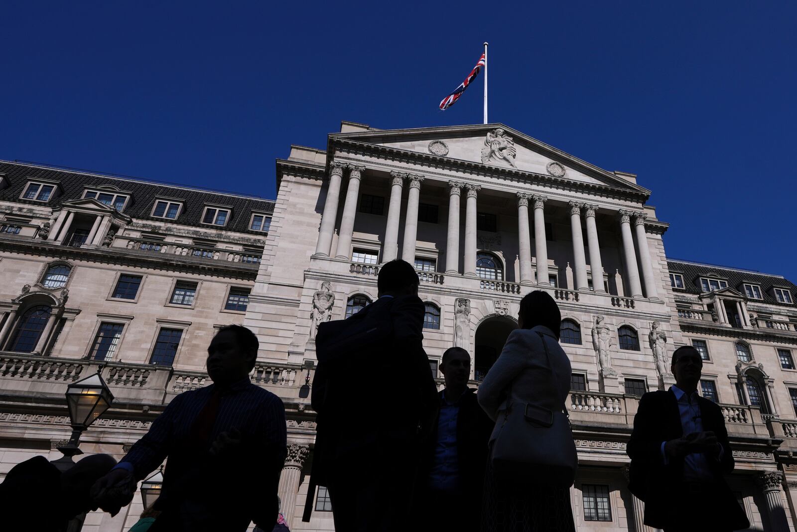 FILE - People are silhouetted as they pass The Bank of England in London, Thursday, April 3, 2025. (AP Photo/Kirsty Wigglesworth, File)