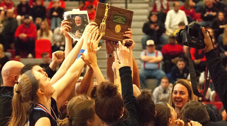 Springboro players and coaches hold up their Division I district trophy and photo of Wayne Kemper, their assistant coach who died this past Sunday. The Panthers defeated Lakota West 71-43 Saturday at Princeton High School. They will play either Loveland or Mount Notre Dame in a regional semifinal at 8 p.m. Wednesday at Princeton. Jeff Gilbert/CONTRIBUTED