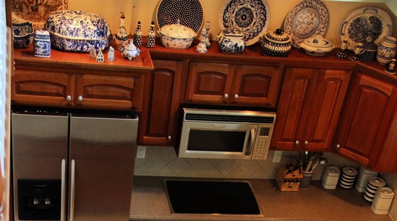 The ceiling above the kitchen/breakfast area rises two stories, accommodating the open walkway and railing on the upper level, which looks across to two large windows, a wide plant shelf and recessed ceiling lights accenting the kitchen work spaces.