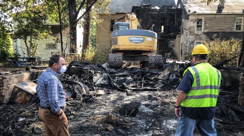 Landlord Joesph Lucas, left, and a Dayton housing inspector survey the damage of a fire that damaged two house and three garages on Wroe Avenue in Dayton Thursday, Sept. 10, 2020. STAFF PHOTO / JIM NOELKER