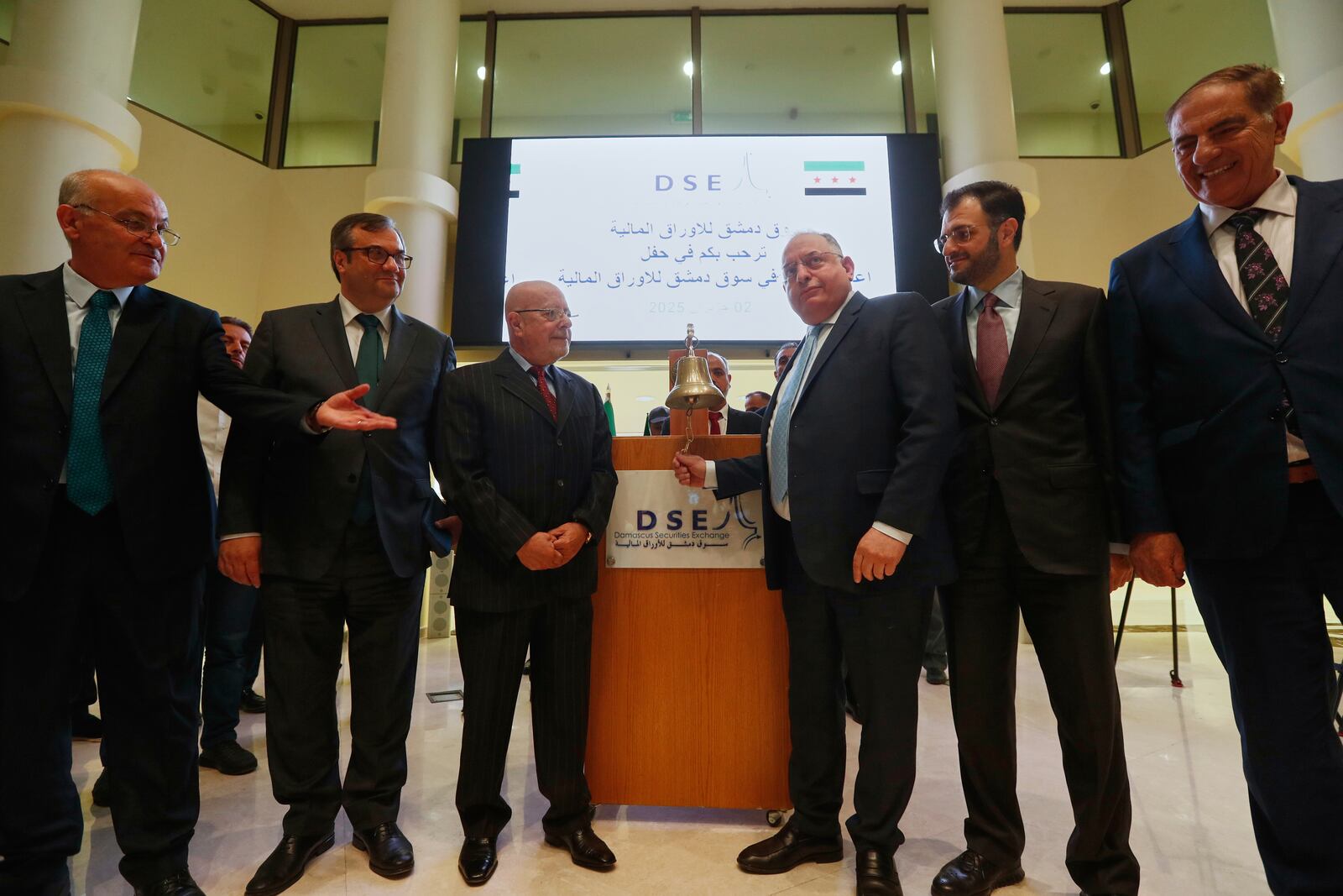 Syrian Finance Minister Mohammed Yisr Barnieh, center right, rings the opening bell at the Damascus Securities Exchange in Damascus, Syria, Monday, June 2, 2025. (AP Photo/Omar Sanadiki)